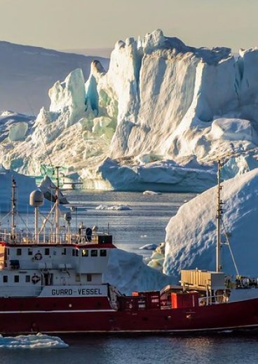 Photographie représentant un bateau naviguant le long de la côte est du Groenland.
