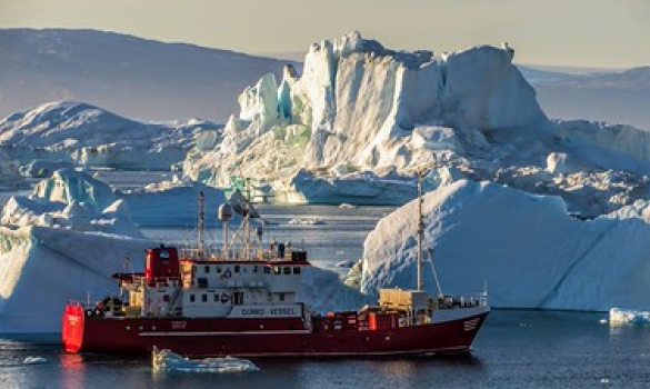Photographie représentant un bateau naviguant le long de la côte est du Groenland.